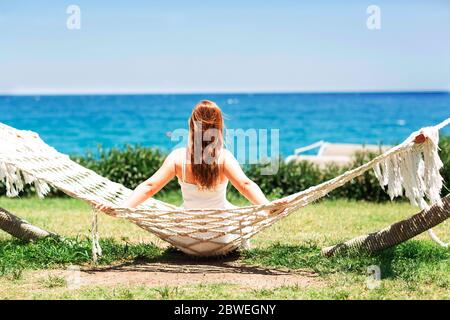 Jeune femme se relaxant dans le hamac sur la plage avec vue sur la mer Banque D'Images