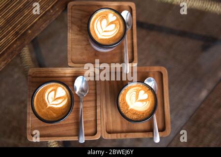 Deux tasses de cappuccino chaud sur l'assiette avec des cuillères sur fond de table en bois blanc. Placer pour le texte. Vue de dessus. Banque D'Images