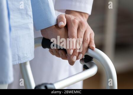 Le physiothérapeute touche la main de la femme pendant qu'elle tient le cadre de marche de près Banque D'Images