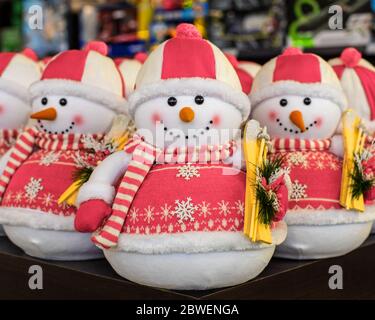 Bonhomme de neige en peluche mignon dans un chapeau et un pull rose avec skis. Décorations du nouvel an, jouets de vacances. Carte de Noël avec bonhomme de neige, gros plan Banque D'Images