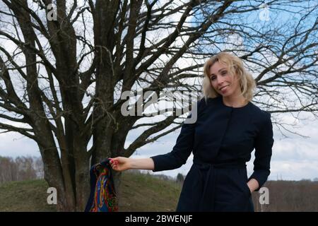une blonde aux cheveux longs jouit de la liberté, une femme d'âge moyen marche seule sur une route de terre parmi les champs verts Banque D'Images