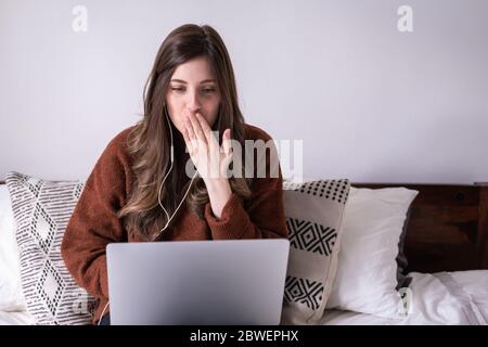 Jeune fille faisant un appel vidéo sur le lit et donnant un baiser à la caméra. Restez à la maison. Distance sociale. Banque D'Images