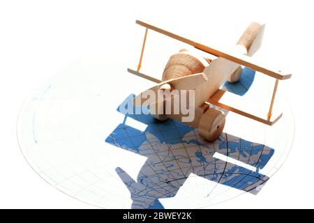 Concept de voyage. Petit avion en bois contre la lumière du soleil avec la carte comme ombre Banque D'Images