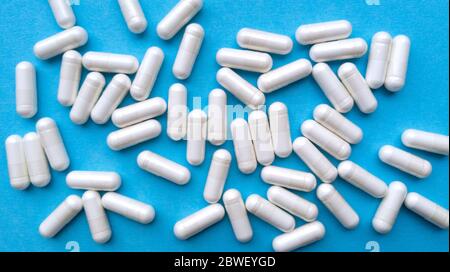 Capsules de pilules blanches sur fond bleu. Simple, plat, texture pastel. Concept médical. Photo. Banque D'Images