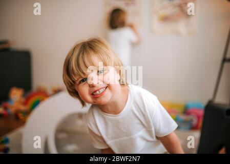 un petit garçon blond rit en regardant l'appareil photo à la maison. famille à la maison. coronavirus. quarantaine. Banque D'Images