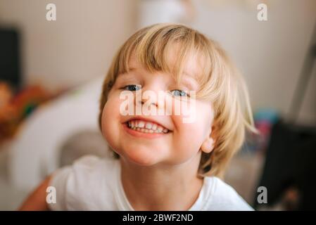 un petit garçon blond rit en regardant l'appareil photo à la maison. famille à la maison. coronavirus. quarantaine. Banque D'Images