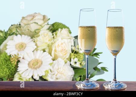 Deux verres de champagne et bouquet flou de fleurs blanches. Banque D'Images