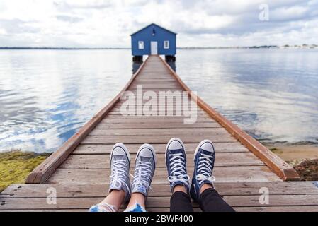 Perth, novembre 2019 : couple touristique portant des baskets profitant de la vue sur la maison de bateau bleue - le hangar de bateau Crawley Edge situé sur la rivière Swan à Perth. Banque D'Images