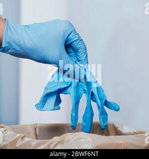 gros plan d'un homme qui jette un gant de latex usagé à la poubelle Banque D'Images