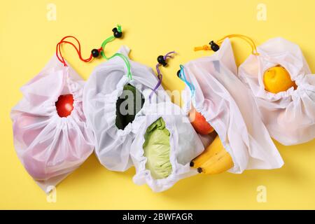 Fruits et légumes dans des sacs en maille écologiques réutilisables sur fond jaune vif, concept zéro déchet. Arrêtez la pollution. Banque D'Images