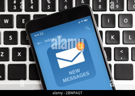 Smartphone avec notification de nouveau message électronique sur l'écran situé sur le clavier de l'ordinateur portable Banque D'Images