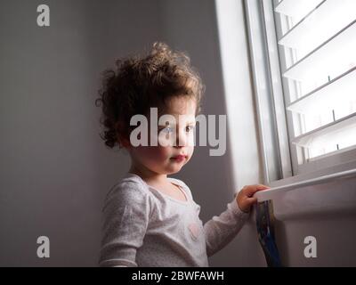 Un enfant de deux ans regarde par la fenêtre Banque D'Images