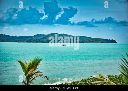 Bateau à vitesse rapide sur les vagues de l'azur Andaman mer sous le ciel bleu près des rives de la belle plage exotique et magnifique de Cenang à Langkaw Banque D'Images