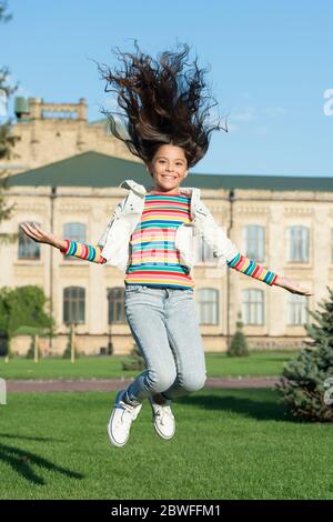 un vrai bonheur. donnez vie à votre enfant. joyeux saut à la hauteur. sens de la liberté. bonheur d'enfance. petite fille avec des cheveux bouclés en plein air. vacances de printemps enfin. enfant célébrant le succès. Banque D'Images