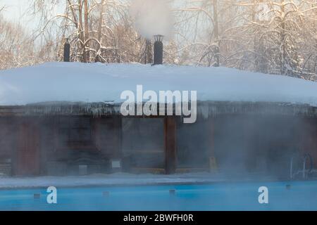 Piscine chaude avec eau bleue et bain russe en bois par temps gelé, extérieur Banque D'Images