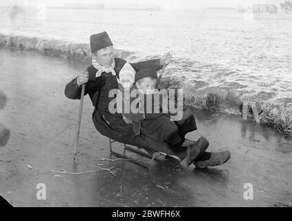 Holland Ice lié Telegrams de l'état de Hollande un gel dur et froid féroce règnent et tous les canaux gelés UN père attentionné adopte la nouvelle méthode de tobogganing de ses enfants à l'école sur la glace en Hollande 10 décembre 1921 Banque D'Images