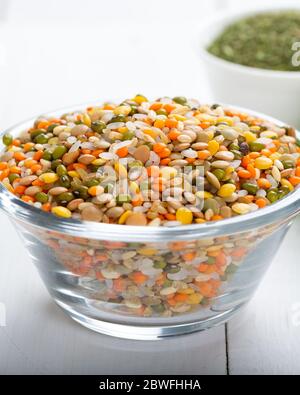 Grains ou lentilles colorés et graines entières ou céréales dans un bol avec légumes frais. Banque D'Images