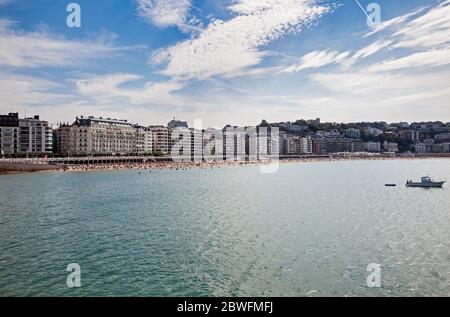 Vue sur le front de mer de San Sebastian, en Espagne, de l'autre côté de la baie, par une journée d'été lumineuse, montrant une plage bondée. Banque D'Images