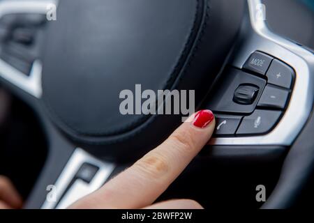 le doigt d'une main féminine appuie sur le bouton d'appel téléphonique sur le volant, l'équipement d'une voiture moderne. gros plan, mise au point douce, arrière-plan flou Banque D'Images