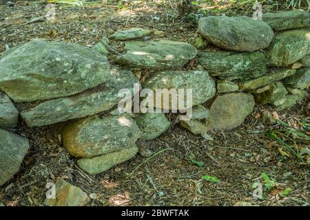 Vue rapprochée de la pierre et du mur de roche empilés et secs recouverts de lichens et de mousse, un mur de soutènement rustique pour les plantes dans un jardin Banque D'Images