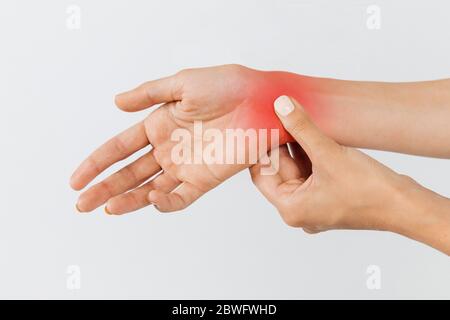 Gros plan des bras féminins tenant son poignet douloureux causé par un travail prolongé sur l'ordinateur, ordinateur portable, coloré en rouge.syndrome du tunnel carpien, arthrite, Banque D'Images