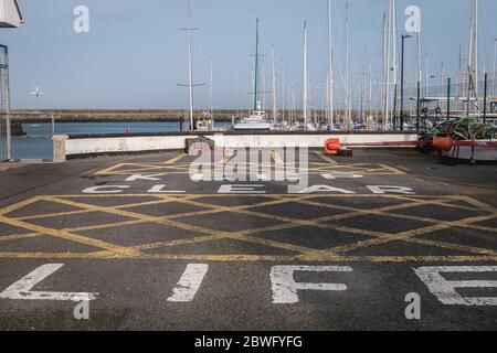 Howth près de Dublin, Irlande - 15 février 2019 : garder la peinture de bateau de vie claire sur le bitume d'une zone d'entretien et de soin de bateau dans le port sur une étendue Banque D'Images