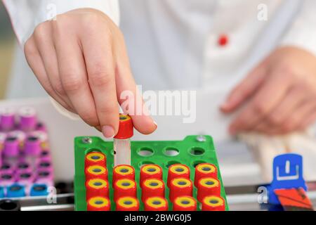 La main de l'infirmière prend les tubes à essai vides du plateau du laboratoire. Banque D'Images