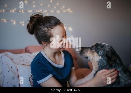 tween fille jouant avec son chien sur son lit Banque D'Images