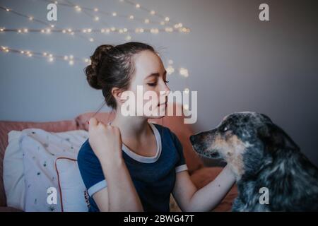 portrait d'une fille intermédiaire avec son chien sur le lit Banque D'Images