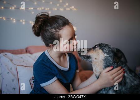 tween fille jouant avec un chien sur son lit Banque D'Images