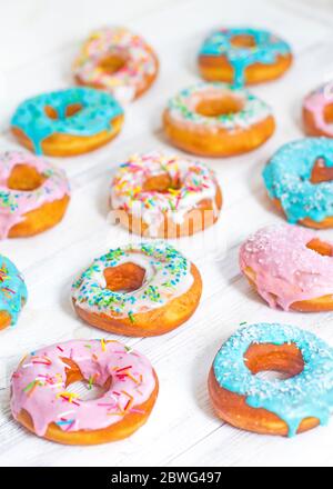 Donuts colorés turquoise et rose, motif. Beignets sur fond blanc. Beignets aux glaçure multicolore. Les beignets sont des pâtes douces traditionnelles Banque D'Images