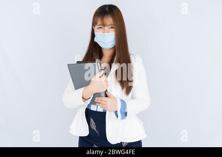 Femme d'affaires asiatique souriante tenant l'ordinateur portable et regardant l'appareil photo sur fond gris. Retour au concept normal. Banque D'Images