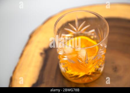 Un ancien garniture avec une tranche d'orange. Le cocktail à base de whisky est sur un panneau de bois. Banque D'Images