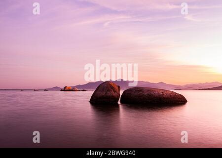 Rochers dans l'eau vue depuis la plage de Palmeiras au coucher du soleil. Florianopolis, Santa Catarina, Brésil. Banque D'Images