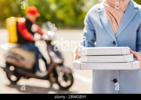 Femme méconnue tenant des boîtes à pizza recevant des aliments du courrier extérieur Banque D'Images