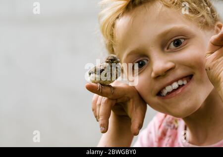 un petit enfant mignon tenant un petit joli petit moineau à la main Banque D'Images