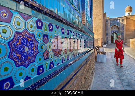 Femme vêtue de la région marchant dans la cour du cimetière Saint de Shah-i-Zinda, à Samarkand, en Ouzbékistan. Banque D'Images