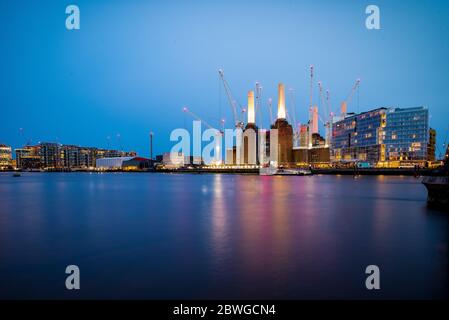 Battersea Power Station et développement riverain au crépuscule, avec des grues et des lumières réfléchies sur la Tamise, Londres, Angleterre, Royaume-Uni. Banque D'Images