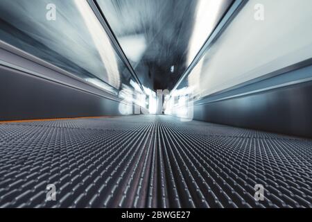 Tournage en exposition longue depuis le fond d'un passage en mouvement dans un terminal d'aéroport; voyageuse à travers la zone de départ contemporaine de la gare d Banque D'Images