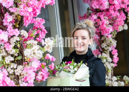 Un joli jeune fleuriste entouré de fleurs à l'extérieur de son magasin dans la zone récemment redéveloppée de Battersea Power Station dans le sud-ouest de Londres. Banque D'Images