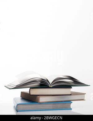 Concept d'éducation. Pile de livres fermés colorés et celui sur le dessus vide et ouvert isolé sur fond blanc. Photo verticale, espace de copie. Banque D'Images