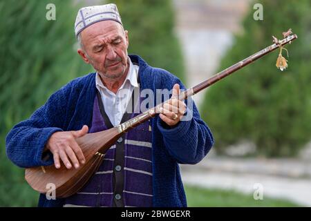 Ouzbek jouant un instrument de musique local, connu sous le nom de Dutar, à Samarkand, Ouzbékistan Banque D'Images