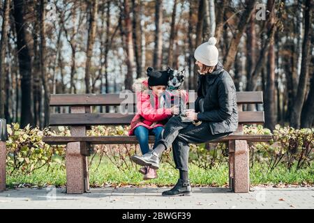 Bonne mère et sa fille avec chien reposant sur un banc Banque D'Images