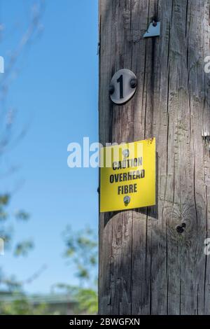 Panneau d'avertissement jaune sur le poteau du réseau téléphonique avertissement du câble à fibre optique aérien. Métaphore rural large bande, large bande dans les zones rurales, rural B/B. Banque D'Images