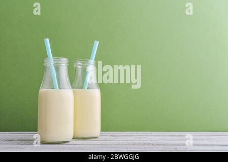 Deux bouteilles de lait et de pailles à boire sur fond vert Banque D'Images