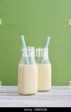 Deux bouteilles de lait et de pailles à boire sur fond vert Banque D'Images