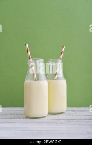 Deux bouteilles de lait et de pailles à boire sur fond vert Banque D'Images
