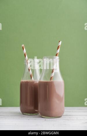 Deux bouteilles de lait au chocolat avec pailles à boire sur fond vert Banque D'Images