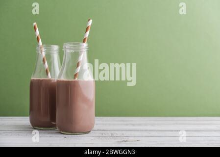 Deux bouteilles de lait au chocolat avec pailles à boire sur fond vert Banque D'Images