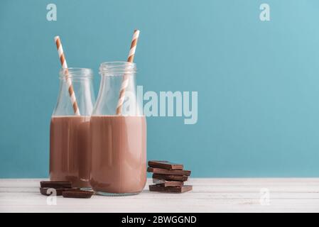 Deux bouteilles de lait au chocolat avec pailles à boire sur fond bleu Banque D'Images